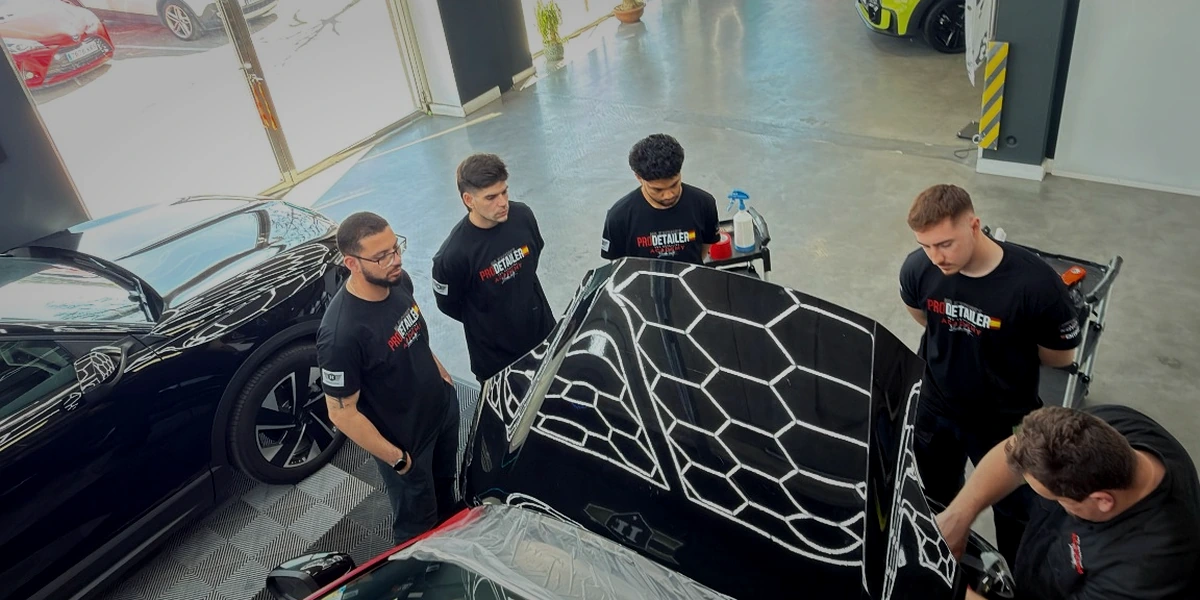 Curso de detailing presencial en Valencia con Leandro Landete supervisando a alumnos sobre un coche de alta gama"